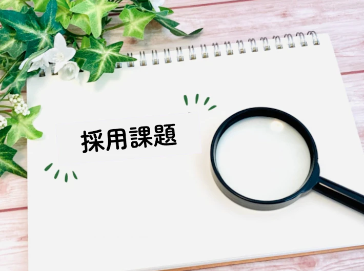 「採用課題」と書かれた画用紙と虫めがね
