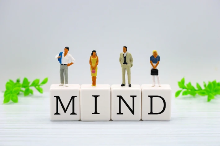 「MIND]と書かれたブロックと会社員
