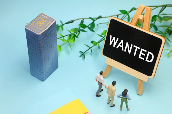「WANTED」と書かれたボードを眺める会社員