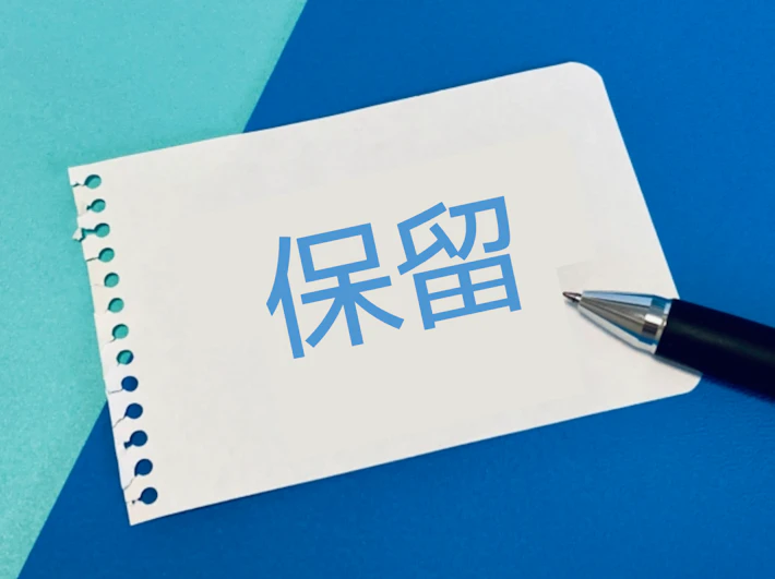「保留」の文字が書かれた紙とペン