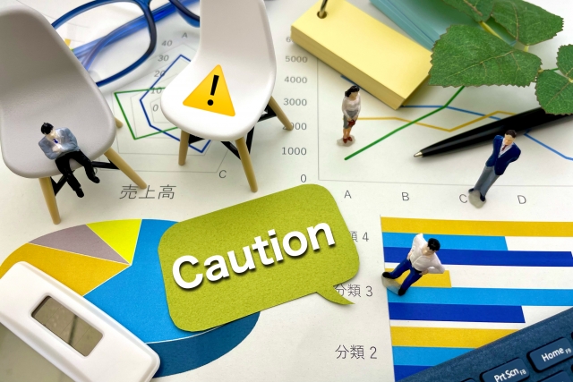 「Caution」の吹き出しと投資の資料