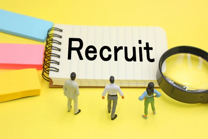 「Recruit」と書かれたメモ帳を見る会社員