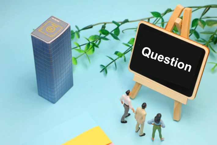 「Question」と書かれたボードを見る会社員