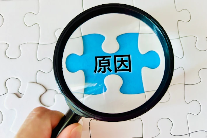 「原因」の文字を虫めがねで見る様子
