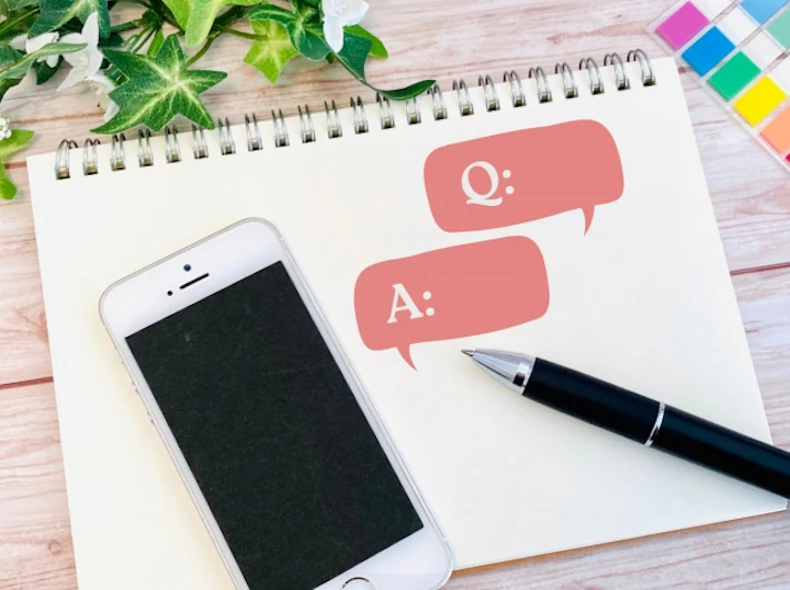 スマートフォンと「Q」「A」が書かれたスケッチブック