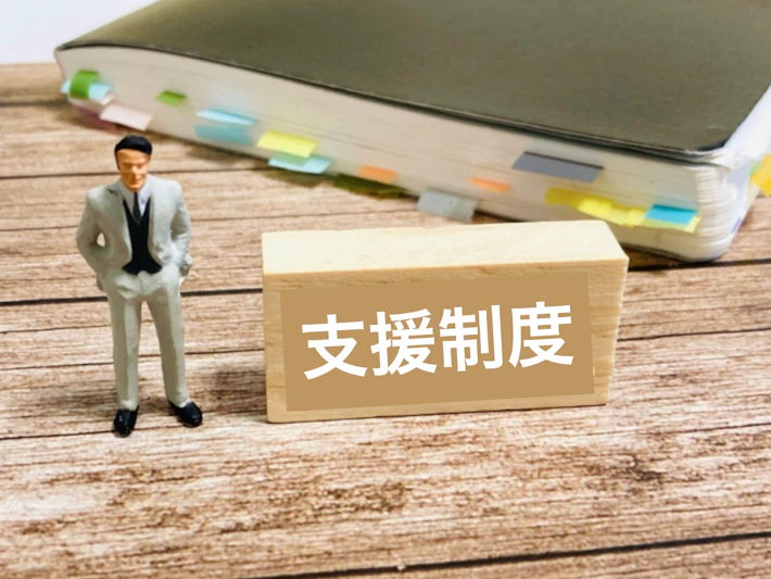 「支援制度」と書かれたブロックと会社員