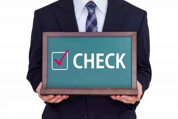 「CHECK」のボードをもつ会社員