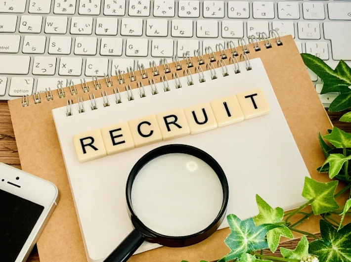 「RECRUIT」の文字ブロックと虫めがね