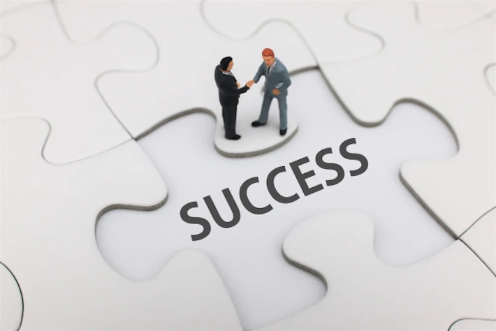「SUCCESS」の文字と握手する会社員