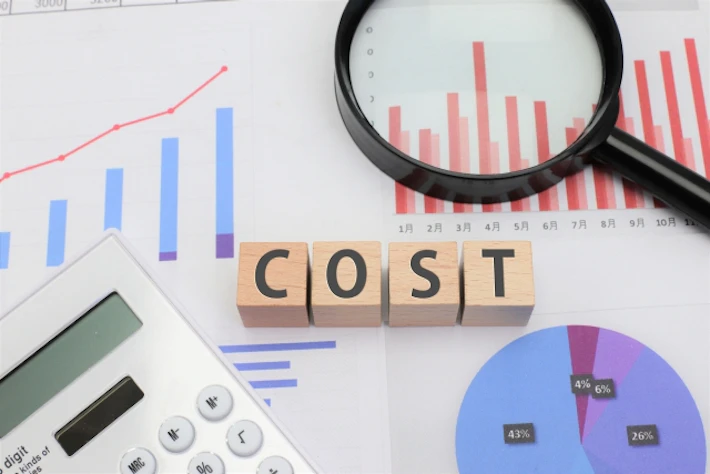 「COST」の文字ブロックと電卓と虫めがね
