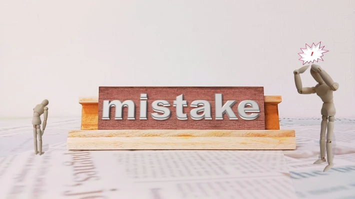 「MISTAKE」と書かれたボードを見る人
