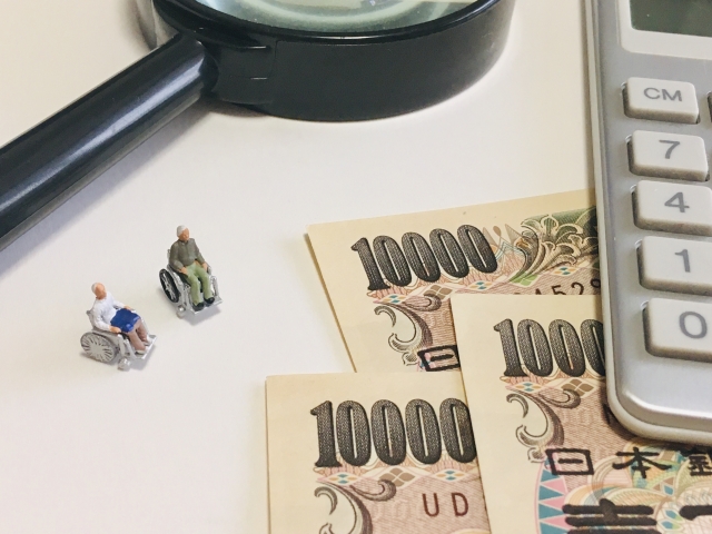 車椅子のシニアと電卓と虫めがね