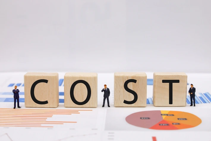 「COST」の文字ブロックと会社員