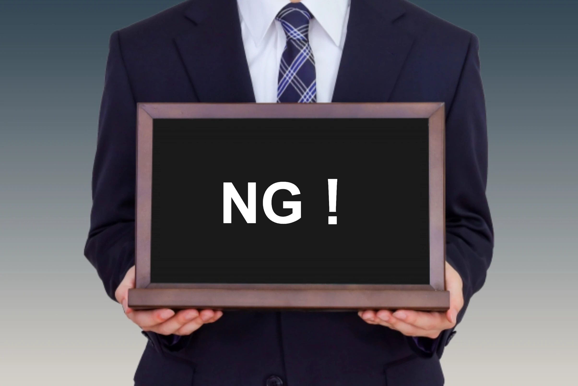 「NG！」と書かれたボードをもつ人