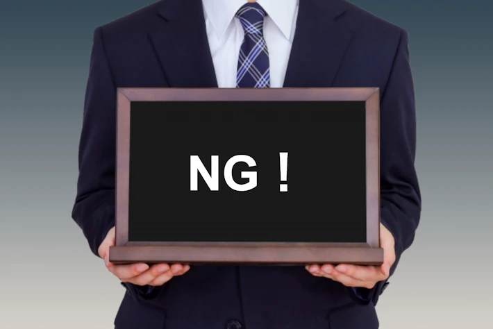 「NG！」と書かれたボードをもつ人
