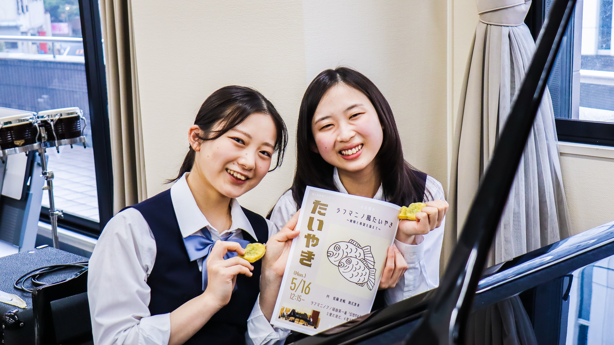 功労賞の副賞で受け取ったお揃いのたいやきキーホルダーと、高3の新歓に出演した際のポスター（阿久津さん作）と、満面の笑顔の2人。