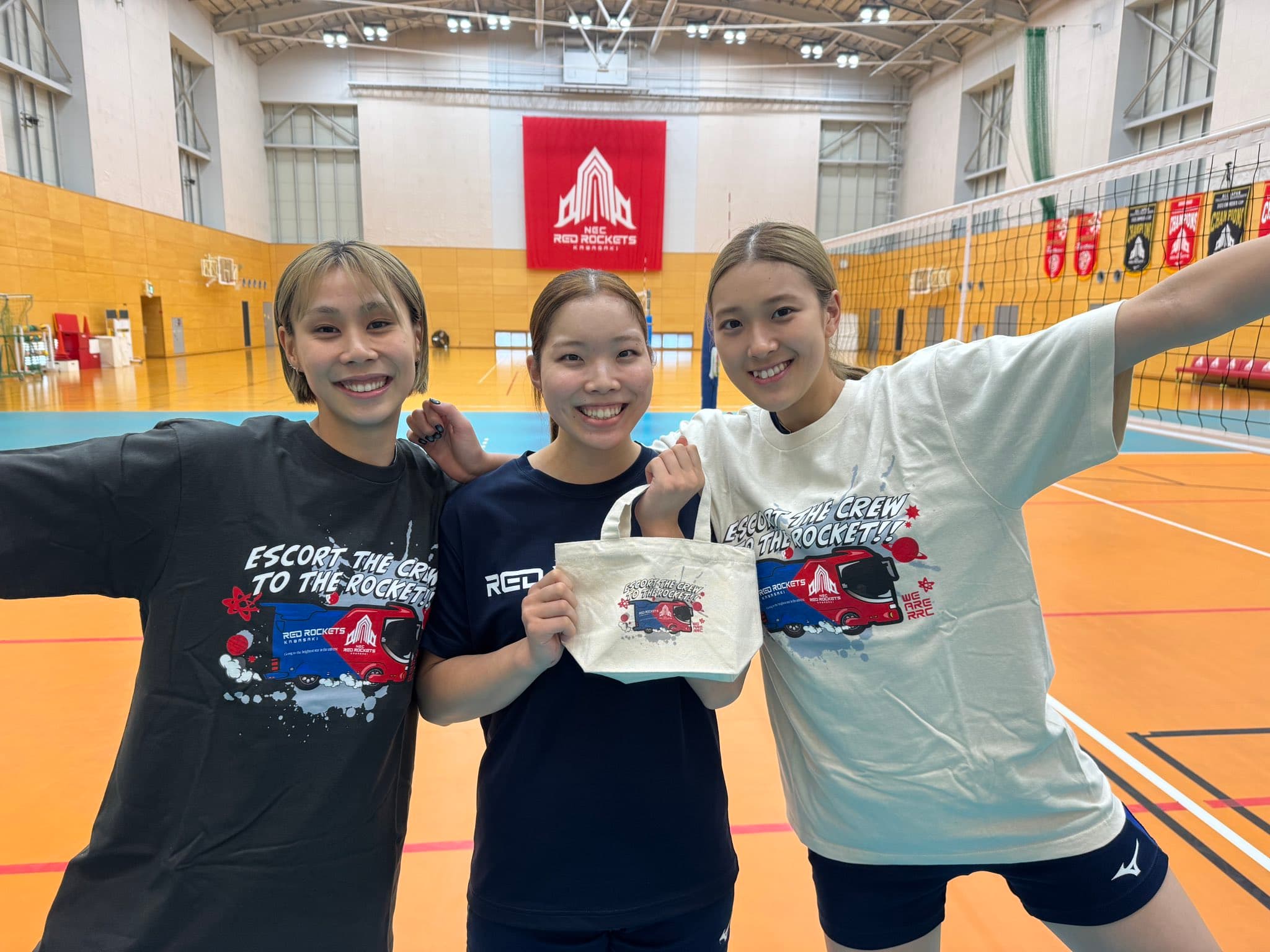 NECレッドロケッツ川崎 グッズ画像：TeamBusTシャツを着ている和田選手・佐々木選手・佐藤選手と、佐々木選手はランチバッグを持っている写真