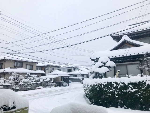 雪が積もった空き家の屋根を除雪する作業員の画像