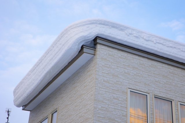 空き家の屋根に積もった雪を下ろす除雪作業の画像