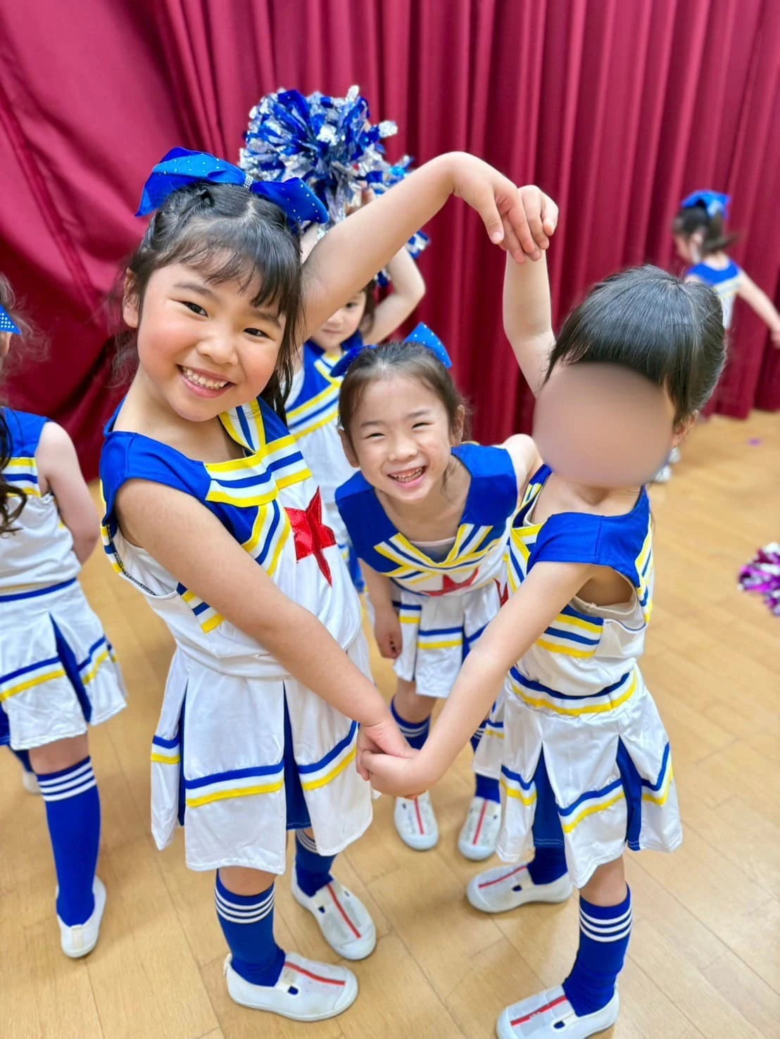 みもみ幼稚園のホール裏でチアダンスの発表会を控えてる衣装を着た女の子