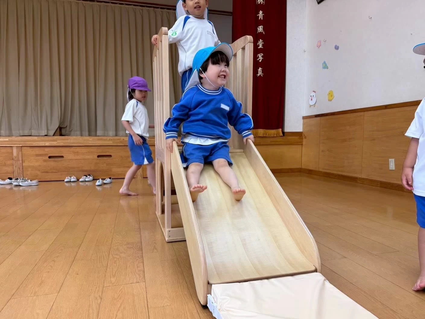 みもみ幼稚園のホールですべり台を楽しむ男の子