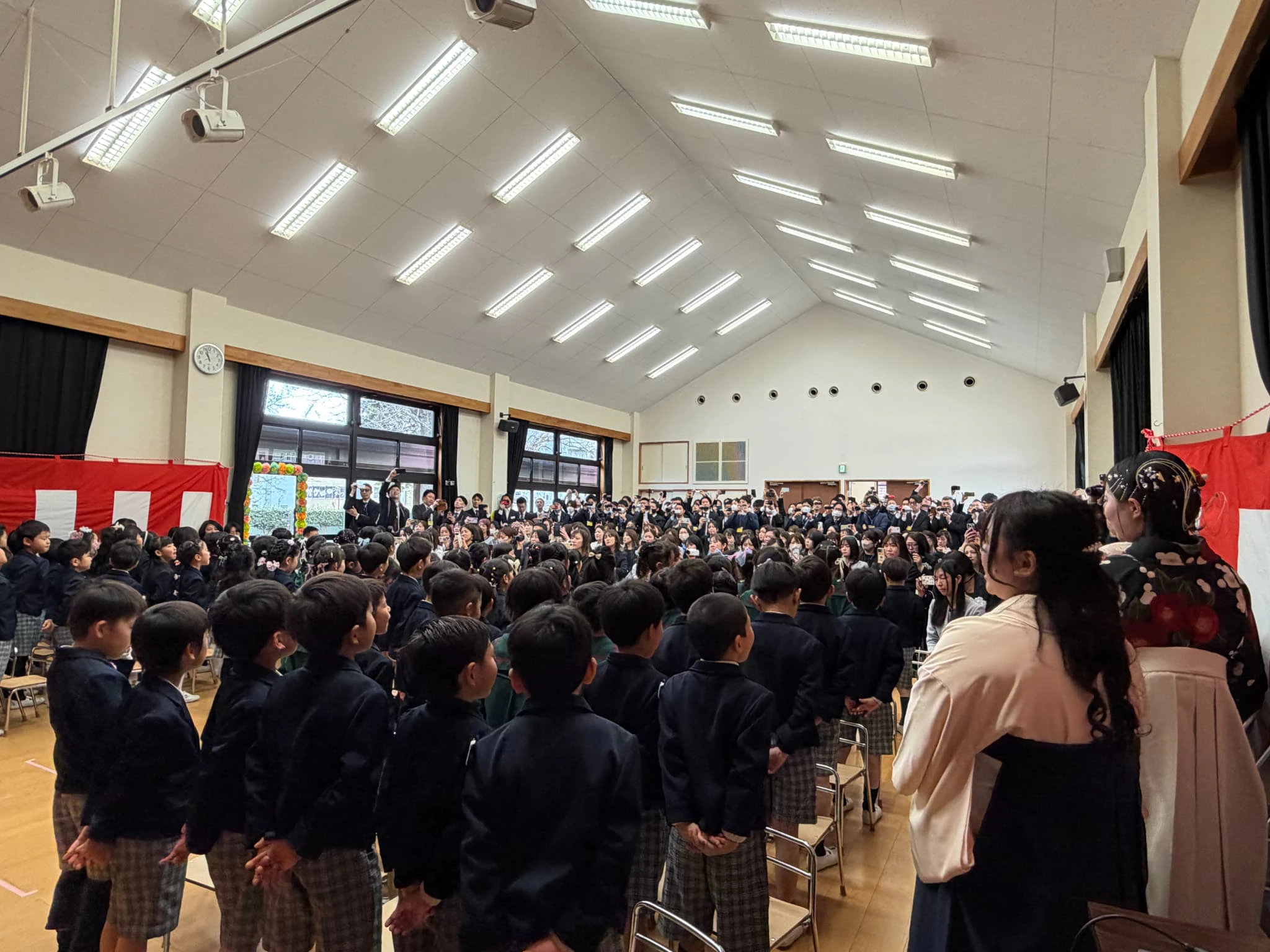 幼稚園のホールで行っている卒園式で、年長さんが保護者の方を向いて歌を歌っている様子