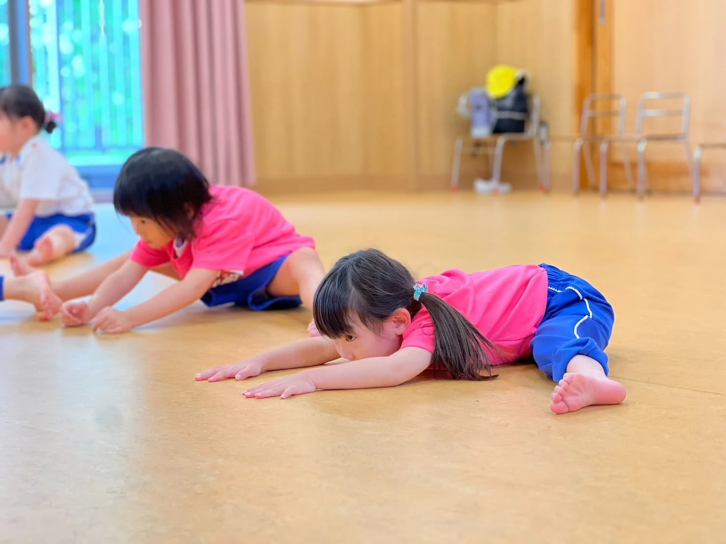 チアダンスの柔軟体操で足を広げ前に倒れている女の子