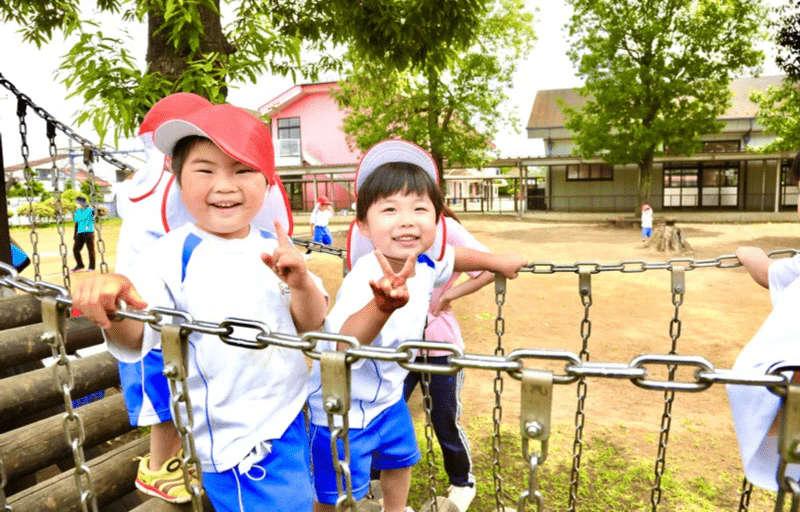 2人の年少の男の子がどんぐり広場のつり橋を渡りながらピースしている様子