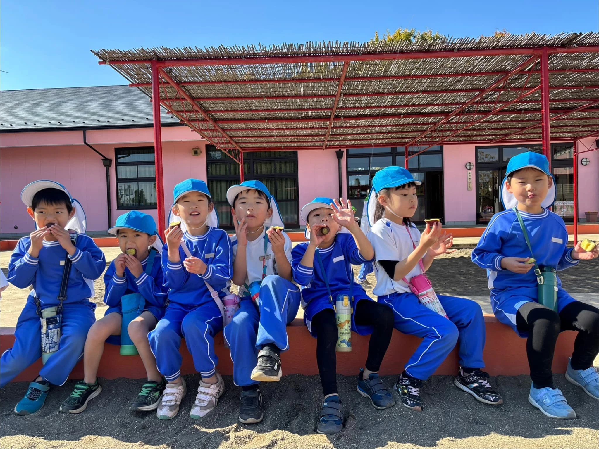 年長組が園庭でさつまいもを食べている様子