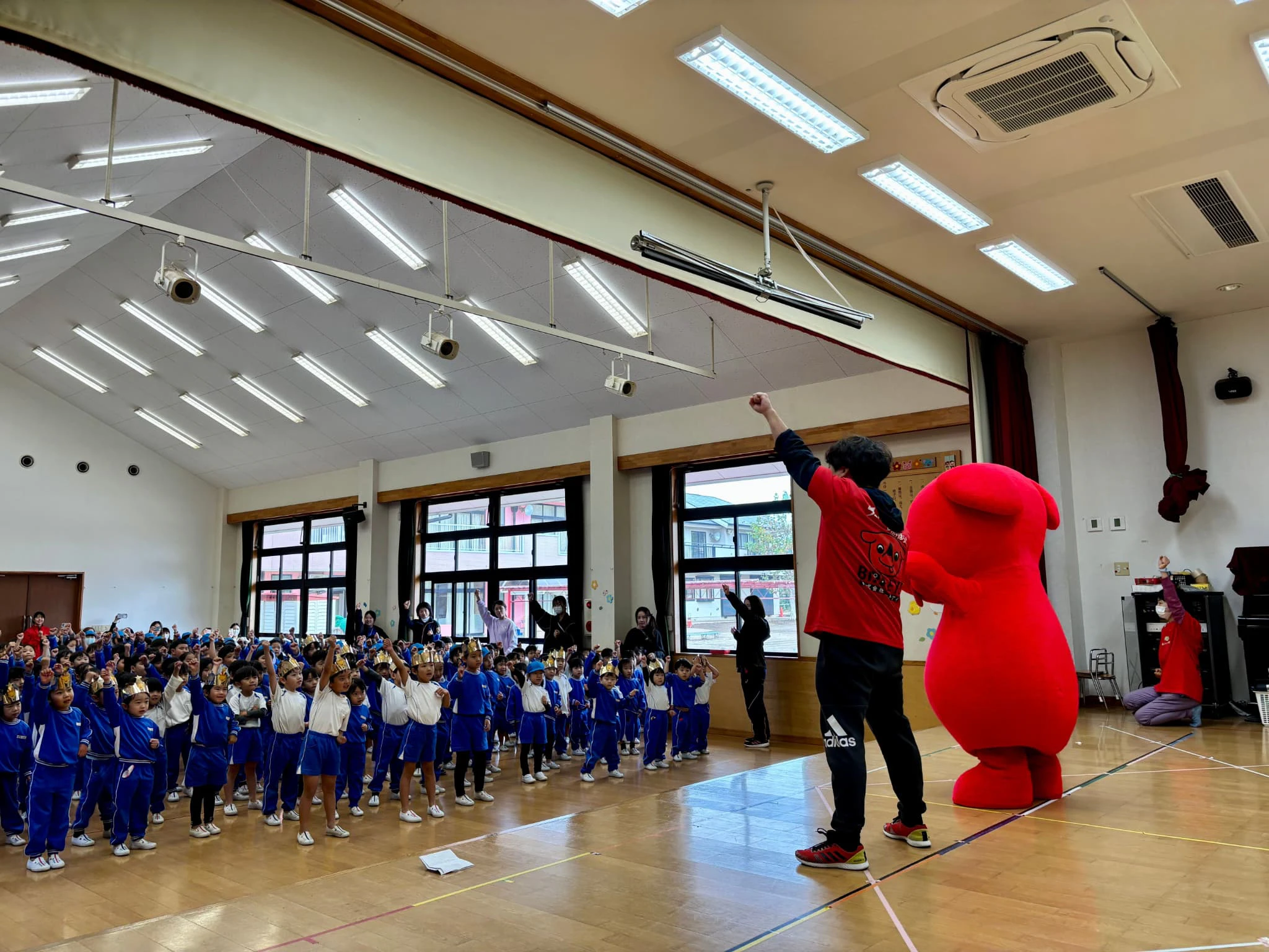 チーバくんが幼稚園のホールで園児たちとダンスを踊ているところ