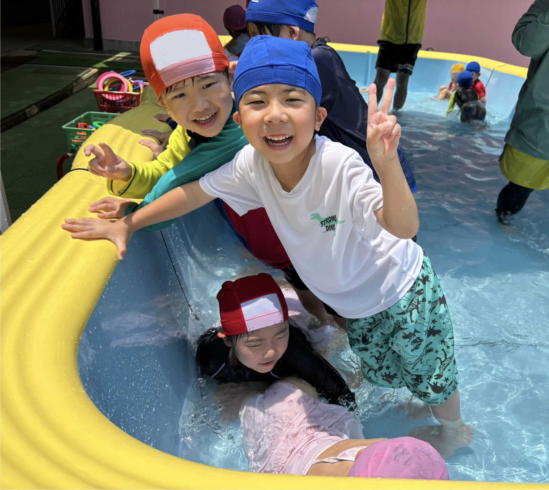 幼稚園のプールに入りピースをしてカメラ目線の年長男の子ふたり