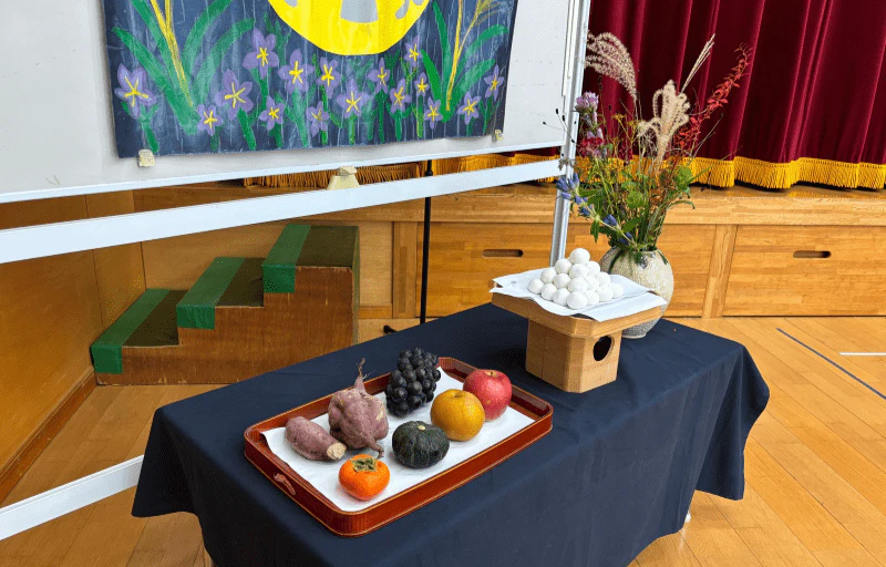 十五夜集会で秋の食物や月見団子、秋の七草が飾られている様子