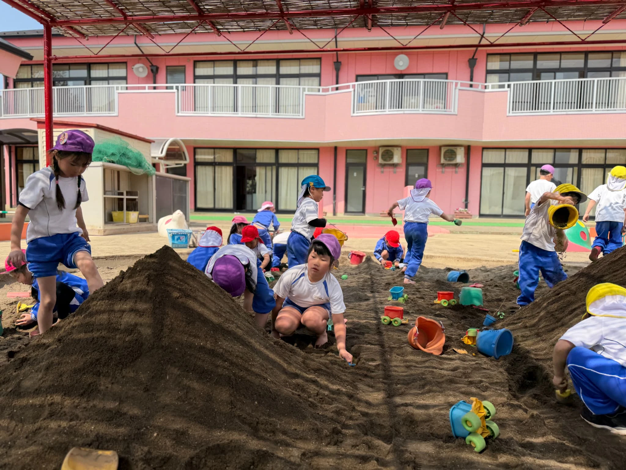砂場で裸足になり大きな山を作る女の子たち