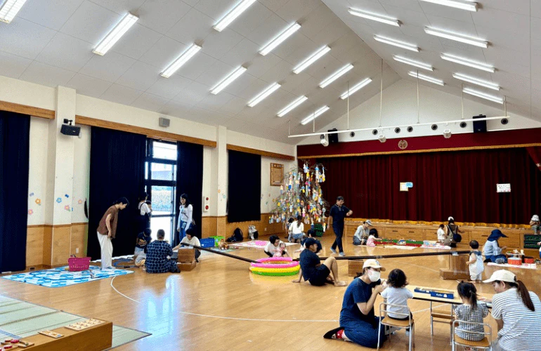 みもみ幼稚園のホールで未就園児の子どもと保護者がおもちゃ製作コーナーなどで遊んでいる様子