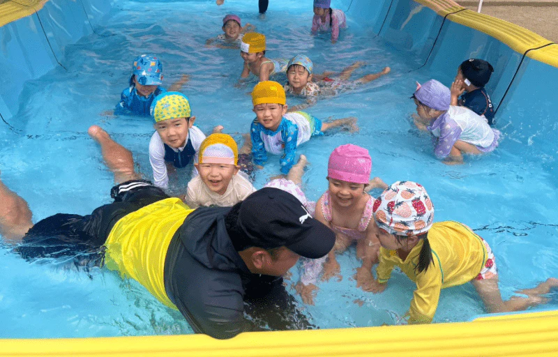 体操の先生と一緒に幼稚園のプールでワニさん歩きをしている年少さん