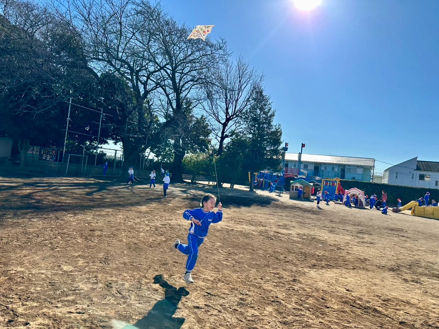 園庭で凧揚げをする年長の女の子