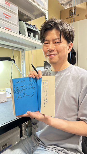 サイン本を持っている西原社長の写真