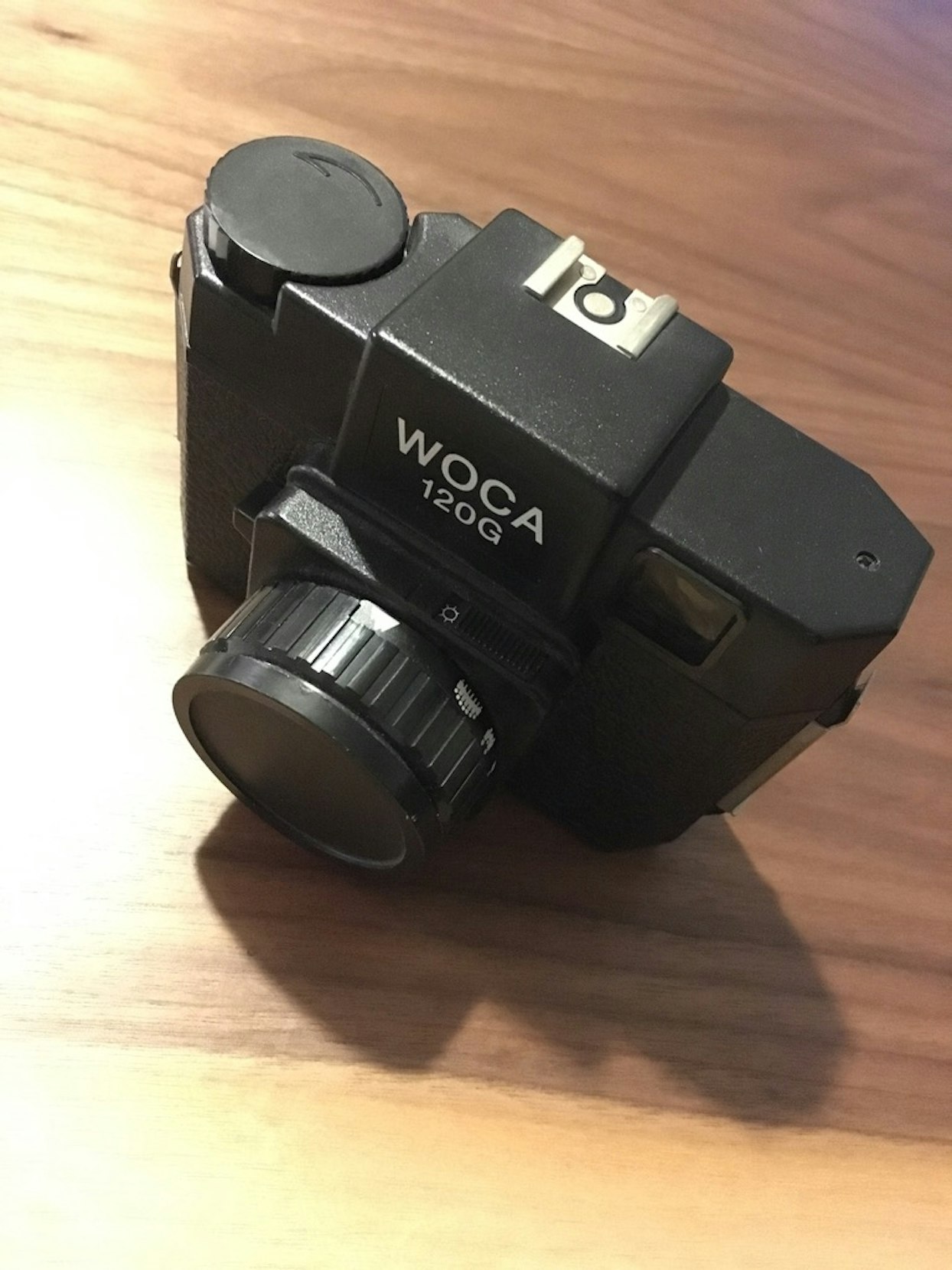 木製の表面に置かれた「WOCA 1506」と刻印された黒いカメラ