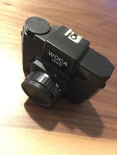 木製の表面に置かれた「WOCA 1506」と刻印された黒いカメラ