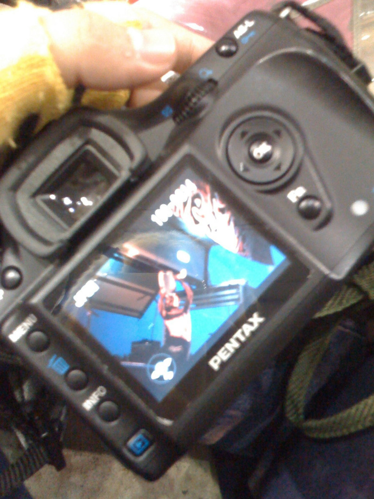 カメラのディスプレイに映る演奏中のギタリストの画像。カメラはPentaxブランドで、ライブ会場での撮影の様子。