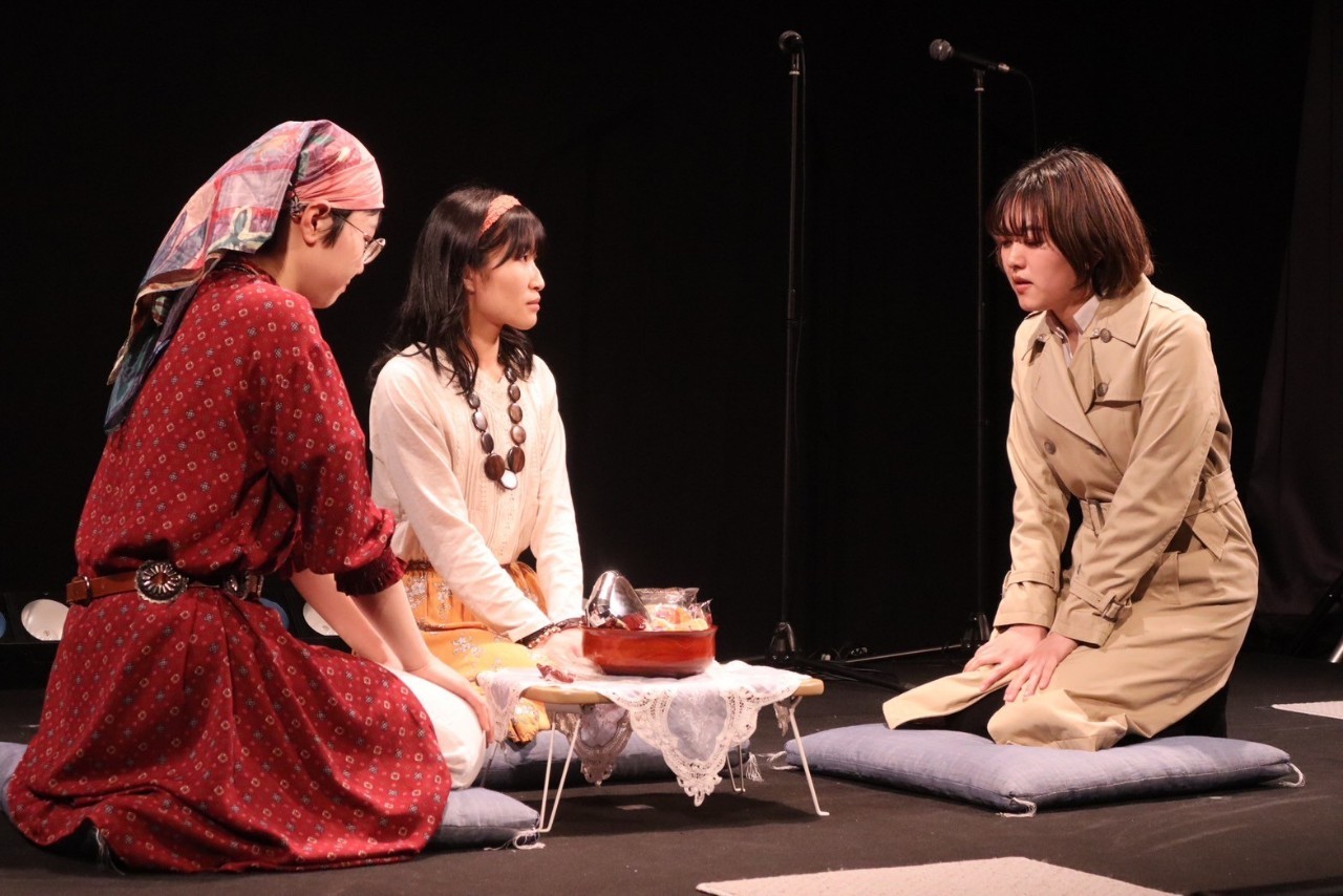 吉報 vol.2での「メタルおにぎり vs. ザ・ワールド」上演写真。小ぶりのちゃぶ台を囲んで出演者のぬまたぬまこ、うめだ、小藤琴が正座している。ちゃぶ台上に置かれた菓子盆の中では、大粒のメタルおにぎりがひときわ異彩を放っている。