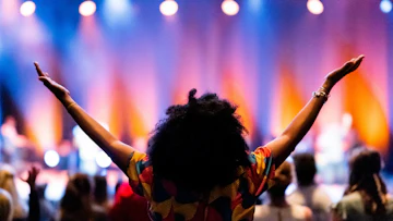 女性がライブで盛り上がり大きく手を広げている様子を表した画像