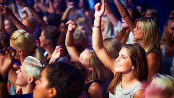 多くの人がライブで手を挙げて歌っている様子