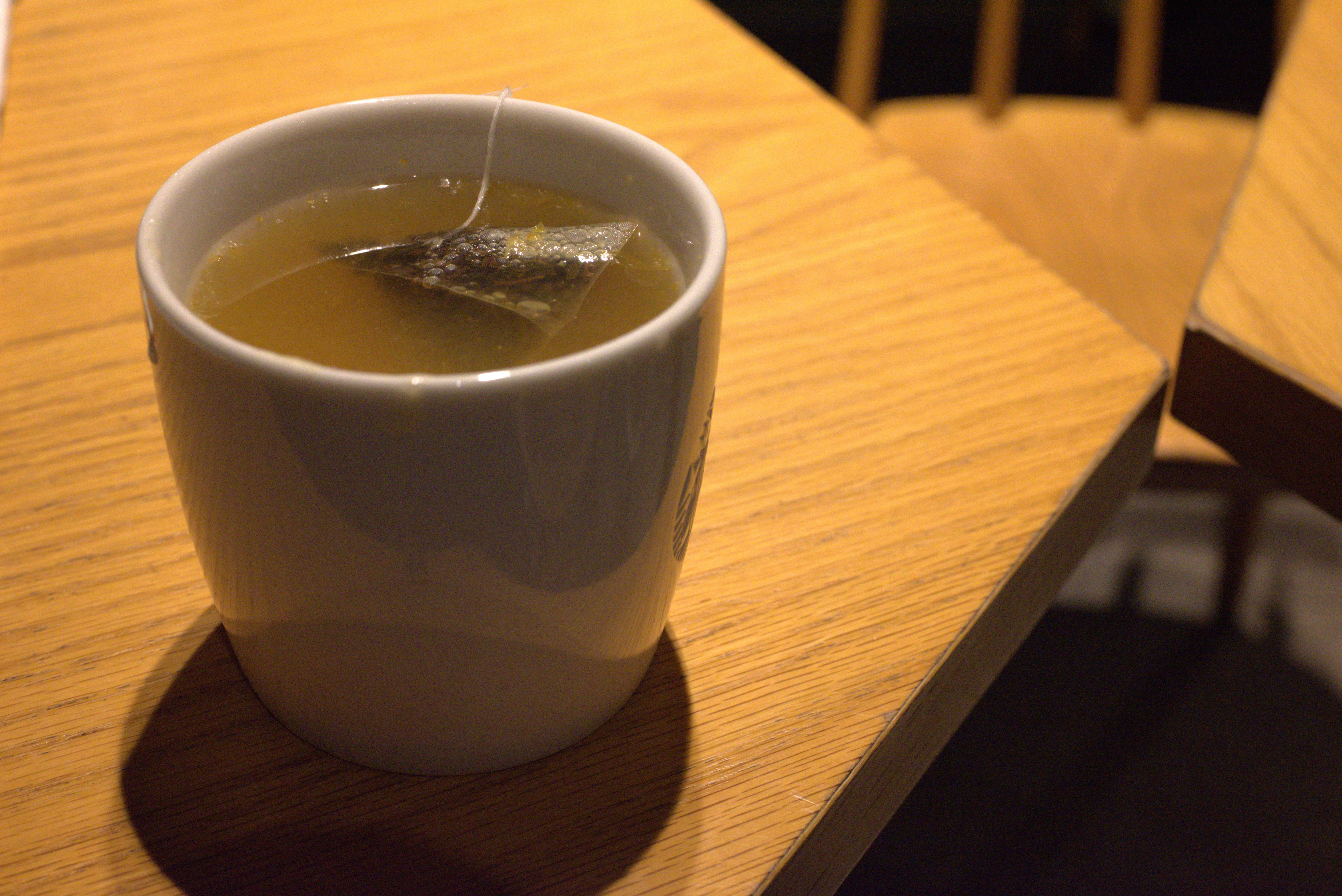 木のテーブルに置かれた温かいお茶のカップ