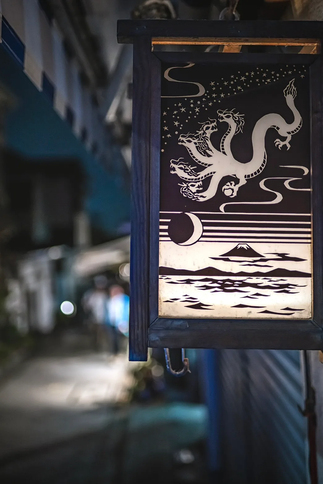 夜の路地にかかる、龍と富士山が描かれた行灯の看板