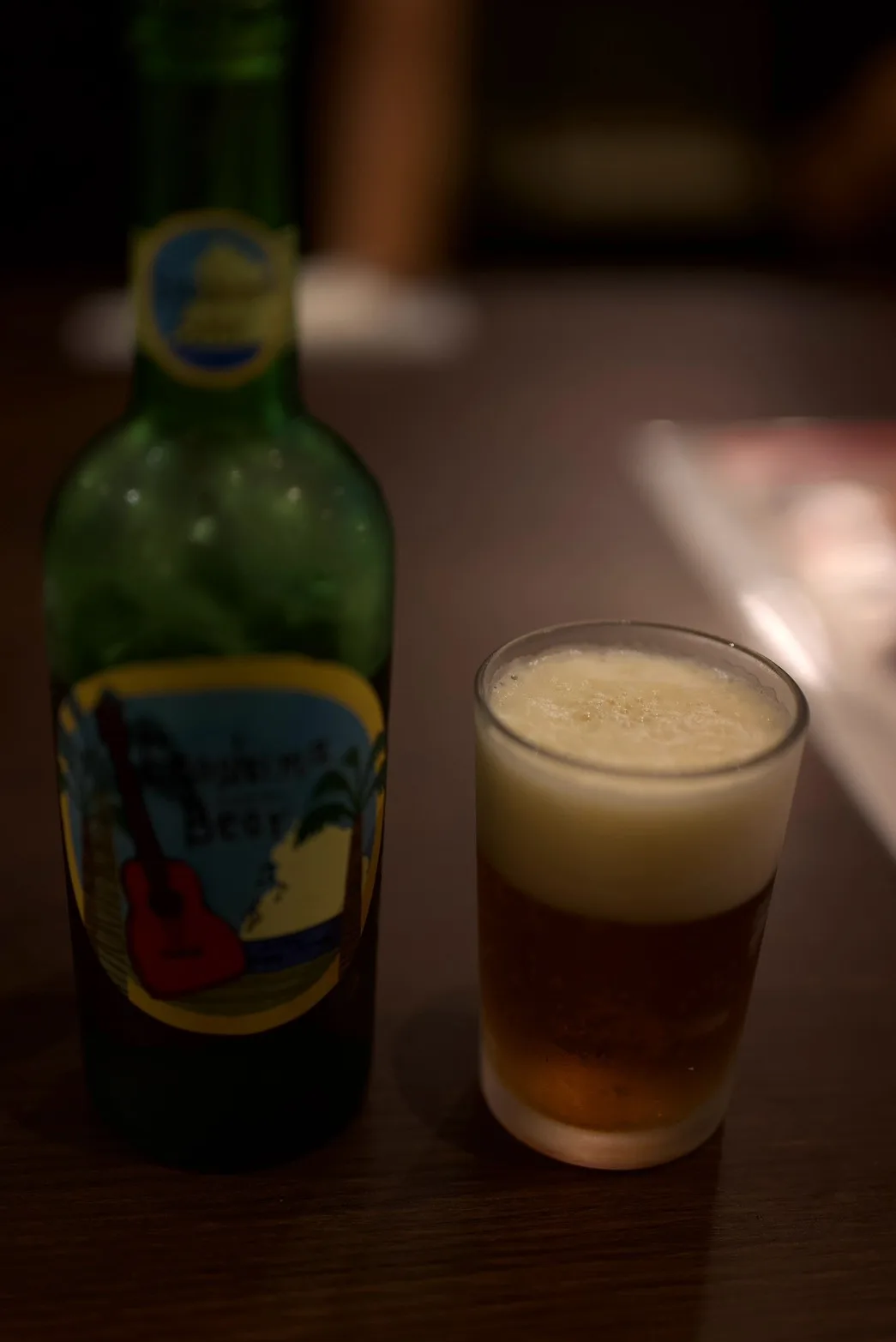 テーブルに置かれた緑色のビール瓶とグラスに注がれたビール