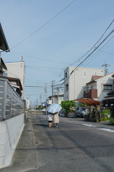 晴れた住宅街を歩く家族の後ろ姿。日常のスナップ