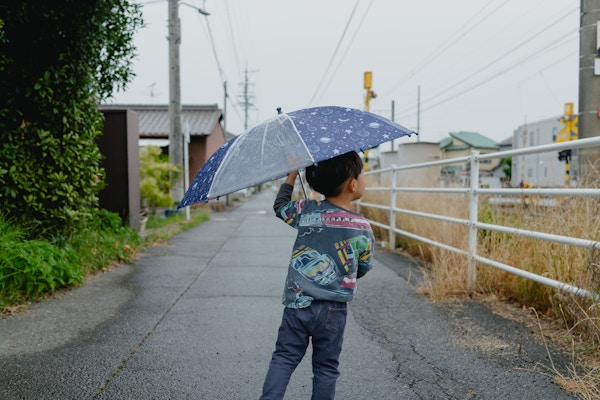 雨の日、傘をさした子どもの後ろ姿。35mmの画角で周囲の雰囲気ごと切り取れる