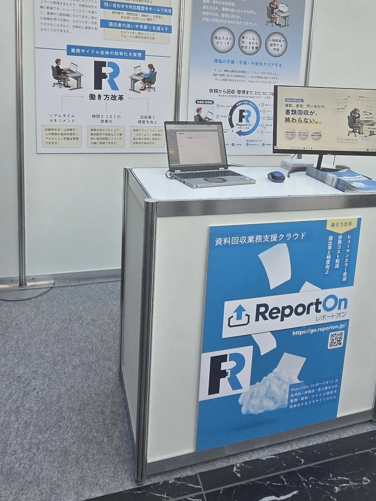 ReportOnのブース。ノートパソコンとモニター、パンフレットを並べた展示台
