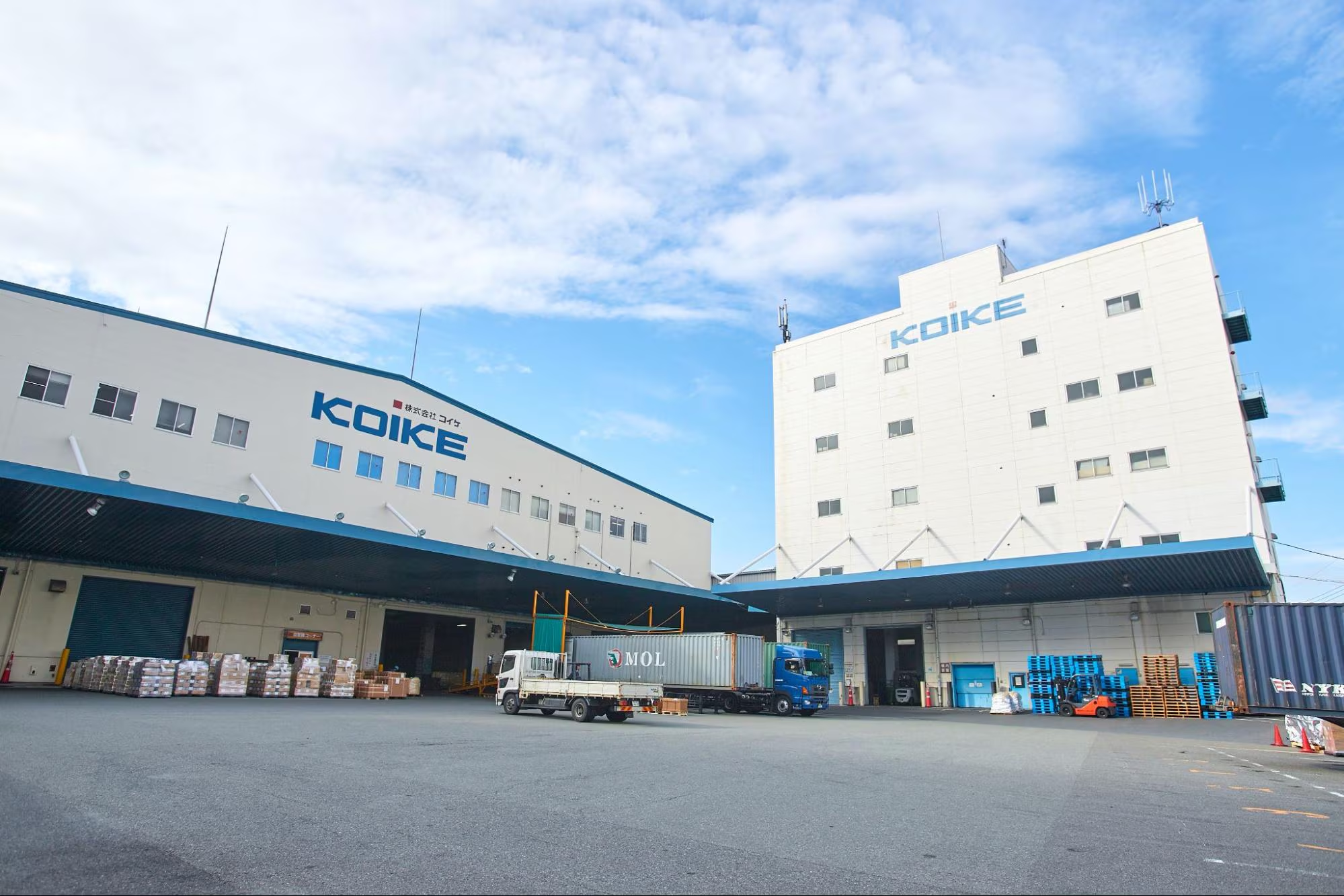株式会社コイケの倉庫・オフィスビル外観と物流車両。